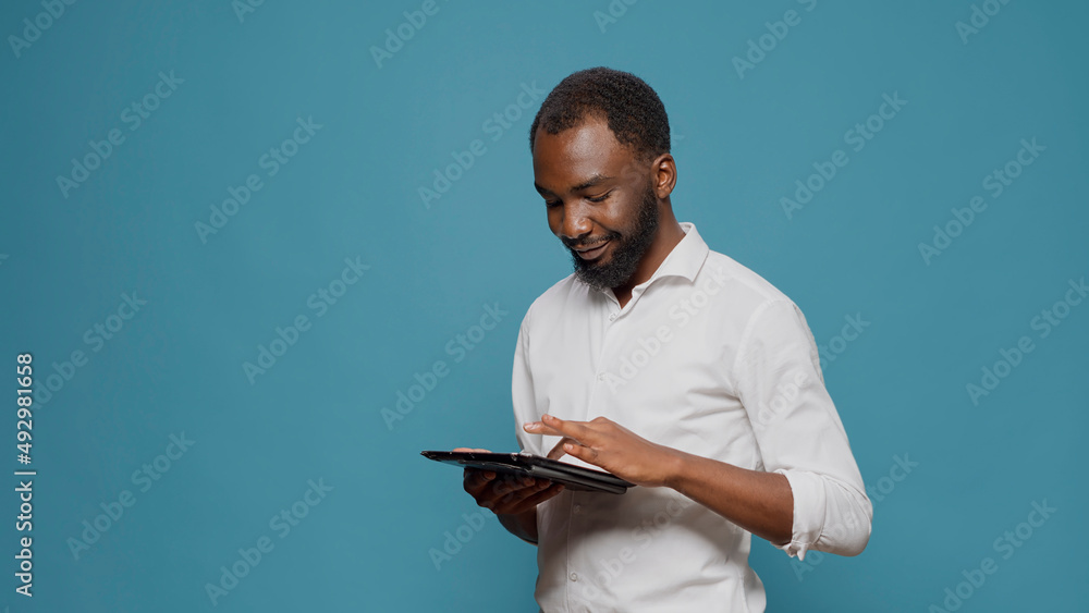 Poster company worker browsing internet on digital tablet in studio, working on internet website to plan su