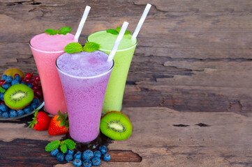 Kiwi strawberry and blueberry smoothies colorful fruit juice green purple and red milkshake blend beverage healthy high protein the taste yummy In glass drink episode morning on wood background.