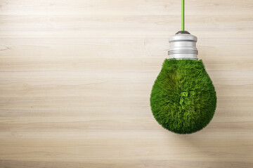 Creative green grass light bulb on wooden wall background with mock up place. Eco concept and...