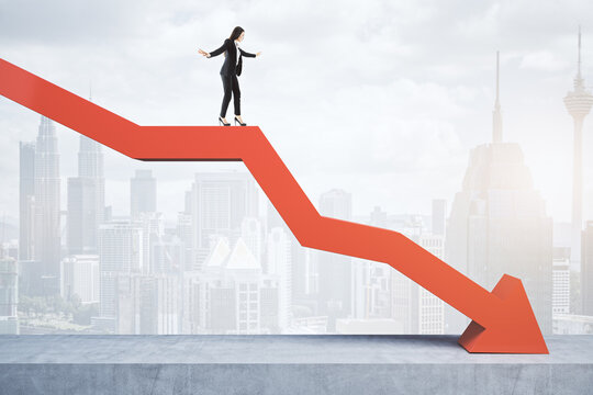 Businesswoman standing and balancing on abstract red downward chart arrow on light city background with mock up place. Down, drop, finance and crisis concept.