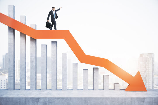 Attractive tiny european man standing and balancing on abstract red downward chart arrow on light city background with mock up place. Down, drop, finance and crisis concept.