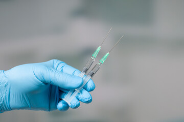 Close up of doctor's hand in medical gloves with two syringes ready for injection