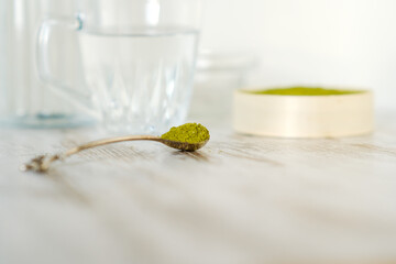 Green herbal detox powder in a plate on wooden table. Superfood. Organic eco health care. Vitamin nutrition and treatment. Immune system support. Alternative medicine. Dietary supplement, bowel clean.