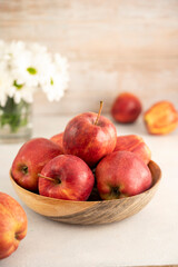 Red apples in bowl on wooden rustic background. Fresh red apple fruits with flowers.