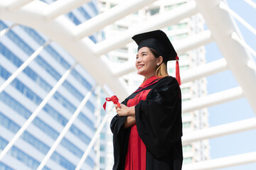 Happy Asian young beautiful graduate female student with University degree standing and holding...