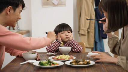 closeup of unhappy Asian preschool boy shaking head and saying no to eat at dining table to his mom...