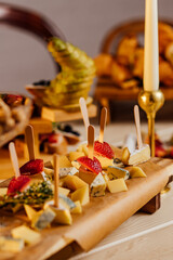 Cheese platter with different cheeses, grapes, nuts, honey, bread and dates on rustic wooden background. Retro styled cheese variety selection on dark wood board.