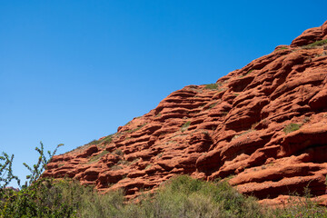Red eroded mountains with blue sky background for wallpaper design. Nature scenic background. Sandstone erosion process due to wind and rains. Dzhuuku gorge.