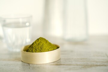 Green herbal detox powder in a plate on wooden table. Superfood. Organic eco health care. Vitamin...