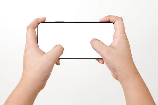 Top View Of Kid Holding Smart Phone . Cell Phone In Kid Hand On A White Background With White Display For COPY SPACE. Game Playing Action Hand Pose.