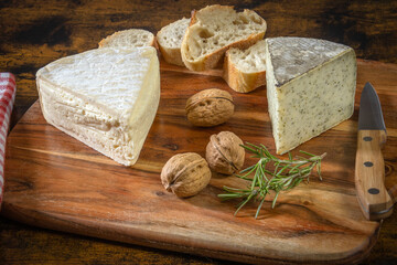 tomme de savoy and tomme with wild garlic on a wooden board with walnuts
