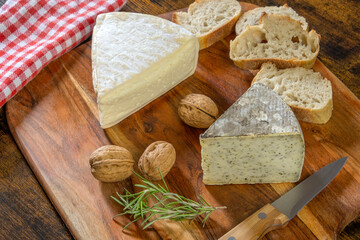 tomme de savoy and tomme with wild garlic on a wooden board with walnuts