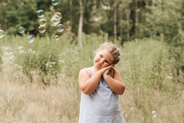 Little blond hair girl play with soap bubbles  in park, family activity during summer. Feeling happiness, joyful, cheerful and enjoying. Playing in garden during sunbeam.