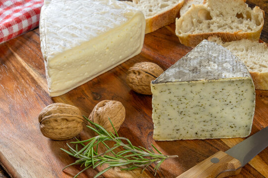 tomme de savoy and tomme with wild garlic on a wooden board with walnuts
