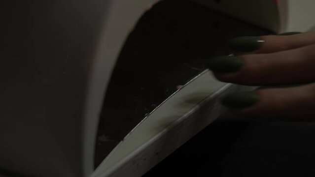 Close up footage of woman hands drying fresh nails with UV.