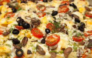 Baked potato slices with vegetables, mushrooms, cheese, dill and olives closeup.