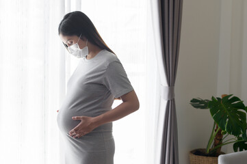 Young pregnant woman wearing a protective mask and expecting a baby, healthy and motherhood concept