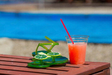 A juicy, summery banner. A glass of freshly squeezed grapefruit juice and flip-flops on a sun...