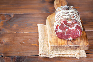 Capocollo of martina franca on wooden table typical from apulia south italy. Italian salami