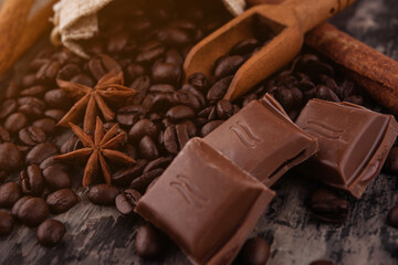 chocolate, cinnamon sticks  and coffee beans on wooden background