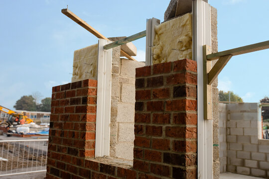 Insulating walls of new build house by placing rock wool inside wall cavities as part of the energy-saving measures