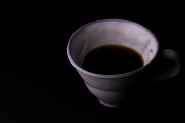 Black Coffee in a white ceramic Cup on Black Background