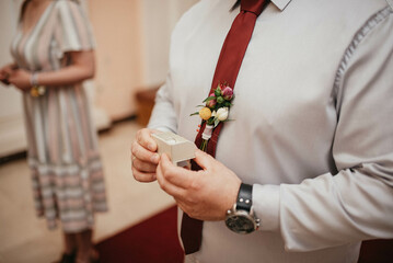 Groom holding wedding rings.