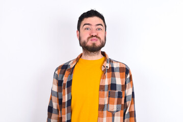 young caucasian man wearing plaid shirt over white background puffing cheeks with funny face. Mouth inflated with air, crazy expression.