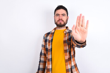 young caucasian man wearing plaid shirt over white background doing stop gesture with palm of the hand. Warning expression with negative and serious gesture on the face.