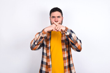 young caucasian man wearing plaid shirt over white background has rejection angry expression crossing fingers doing negative sign.