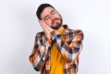 Relax and sleep time. Tired young caucasian man wearing plaid shirt over white background with...