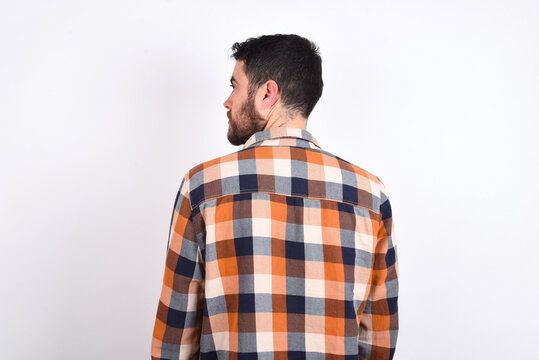 The Back View Of Young Caucasian Man Wearing Plaid Shirt Over White Background Studio Shoot.