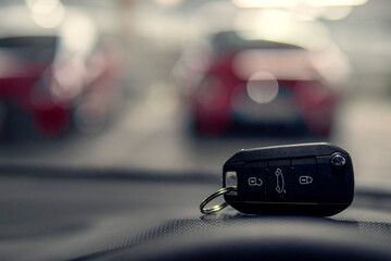 Remote car key on dash board in focus. Car park out of focus in the background. Transportation...