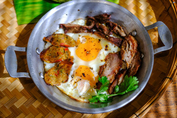 Pan-fried eggs with toppings on the wooden table.