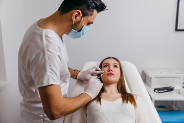 Young brunette woman receiving plastic surgery injection on her face