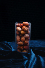 Healthy dried fruits. Dates in a glass on a dark background with side illumination - obrazy, fototapety, plakaty