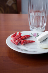 The population is starving from the war. A piece of sausage with cheese on a plate