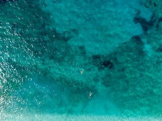 Swimmers in the sea at summer. Tourists diving and swimming in the water, aerial drone view. Transparent sea water in bay.