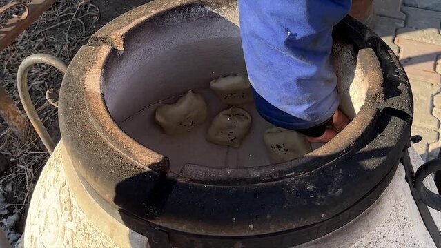 Uzbek samosa cooked on tandoor. Hand placed uncooked samosa  in a special oven  tandoor for cooking. Street asian food.