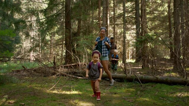 Family with small children walking in summer forest.