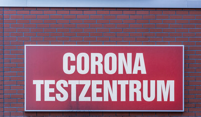 An einer Hauswand ein Schild mit der Aufschrift Corona Testzentrum