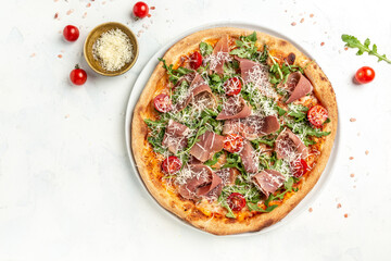 Appetizing italian pizza with cheese, prosciutto, arugula and parmesan. Baked pizza with salami, prosciutto red sauce and cheese. Top view