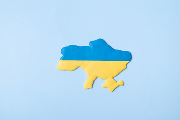 Shape of Ukraine in yellow-blue colors of the national flag on a blue background top view