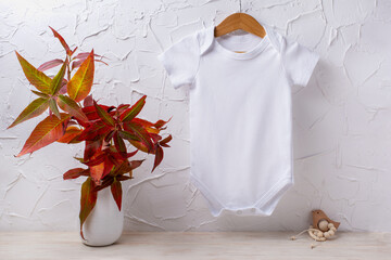 White baby short sleeve bodysuit mockup with red grass and wooden toy