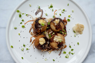 A plate of takoyaki over a marble table