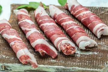minced meat wrapped in bacon on cast iron plate. chevapchichi or Kofta kebab. raw sausages of ground beef or pork with onions and spices wrapped in bacon