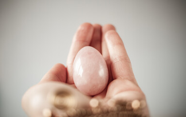 woman holding in hand a vaginal (yoni) egg. Rose quartz crystal jade egg. Copy space