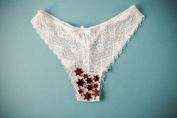 white lace panties with glitter on blue background. Menstruation, woman's health, virginity, first...