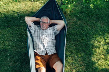 relaxed retired man lying on hammock - senior man on vacation in summer leisure time