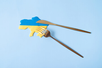 Yellow and blue Ukrainian map with fork and knife, top view. The concept of the appetite of the...